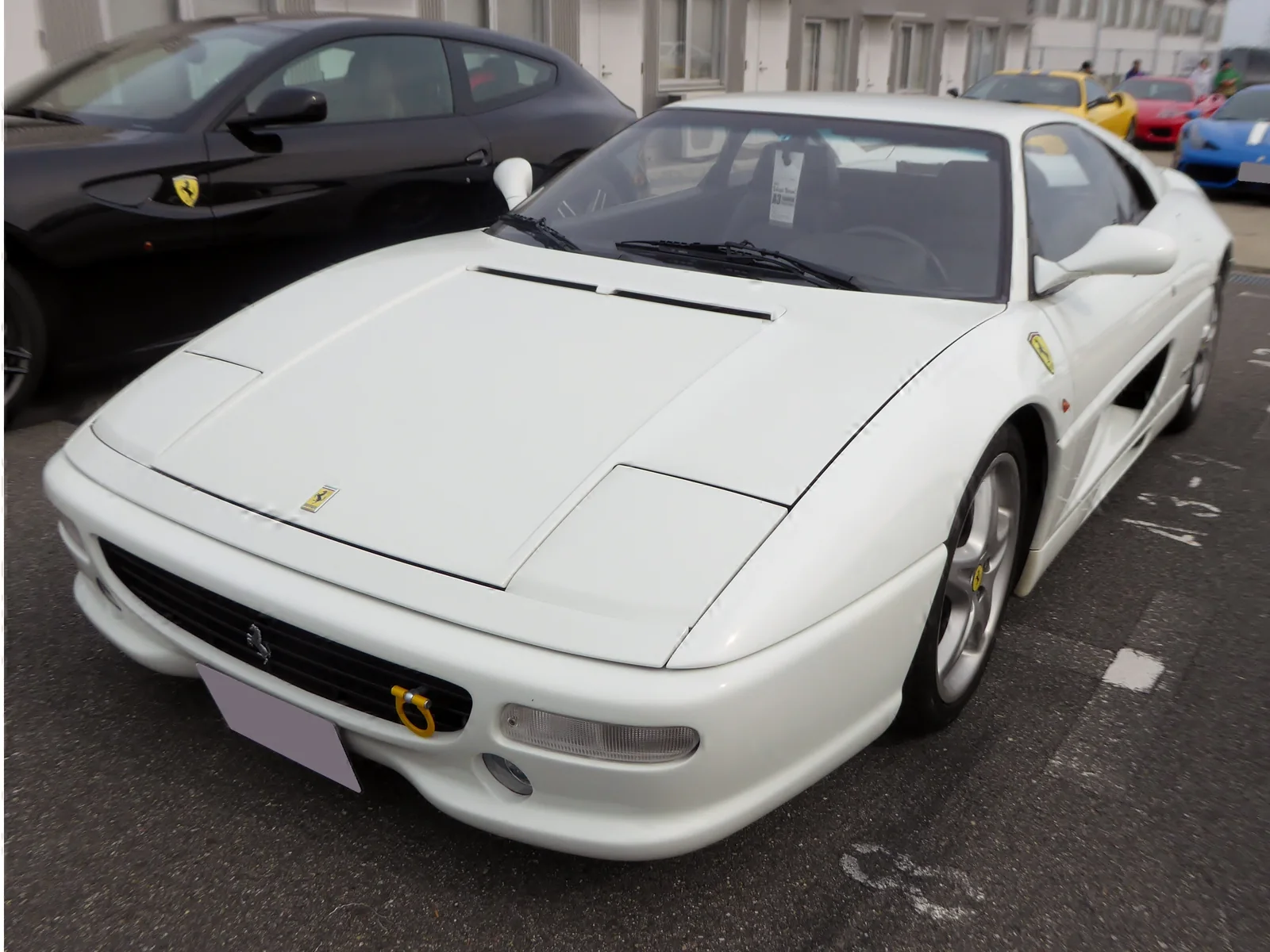 White Ferrari F355 Berlinetta parked outdoors among other sports cars.